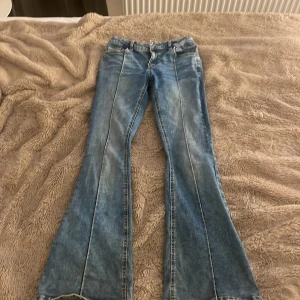 Blå bootcut jeans från Lindex - Säljer ett par ljusblå bootcut jeans från  med markerade sömmar framtill. Säljer pga för små, slitna vid fötterna-syns på bild