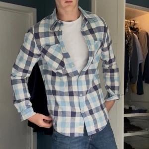 Rutig skjorta Denim & Supply Ralph Lauren - Snygg rutig skjorta från Denim & Supply Ralph Lauren i blått, vitt och marinblått. Skjortan har två bröstfickor, klassisk krage och knäppning framtill. Tillverkad i mjuk bomull och har lång ärm. Perfekt nu för hösten.