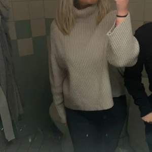 Beige ribbad polotröja - Säljer en beige polotröja med ribbad struktur och lång ärm. Tröjan har en hög krage och är lite loose i passformen, 