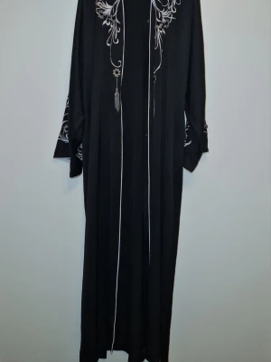 Svart festlig abaya i storlek 56 - En svart festlig abaya i storlek 56 från abayabuth. Har använt den endast en gång och den är i nyskick. Fick den som present och den passade inte mig, i vanliga fall har jag abayas i storlek 58 då jag är 170cm. 