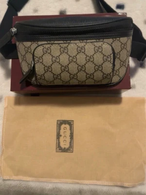 Gucci beige axelväska med GG-mönster - Säljer en beige axelväska från Gucci med klassiskt GG-mönster och svarta detaljer. Väskan har justerbar rem, flera fack med dragkedja och levereras med original dustbag och låda. Perfekt för dig som vill ha en snygg och praktisk väska med lyxig känsla.helt ny aldrig använd kommer med allt i bilderna tar byten bror på vad och pris kan alltid diskuterar 