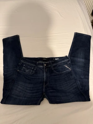 Replay Blue Jeans mörkblå jeans - Säljer ett par Replay Blue Jeans i mörkblå tvätt med klassisk femficksdesign och snygga kontrastsömmar. Jeansen har rak passform och normal midja, med Replay-logga på bakfickan och läderpatch i midjan. Perfekta för dig som gillar stilrena och tidlösa jeans. Oanvända replay byxor W34 L32