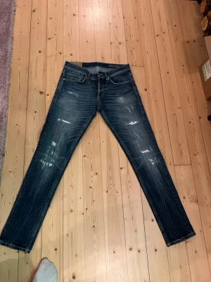 Dondup jeans - Säljer ett par mörkblå skinny fit jeans från dondup med slitna detaljer och snygg tvätt. Jeansen är i väldigt bra skick då dom knappt är använda! Storlek w32.  41cm i midjan och 102cm långa.