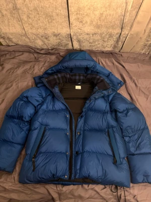 Burberry Detachable Sleeves Puffer Jacket For Men - Burberry jacka i nyskick, knappt använd då blå inte riktigt är min färg. Nypris när jag köpte den är 14200kr. Storlek M, kan göras till väst, multifunktionell jacka. Pris kan diskuteras vid snabb affär.