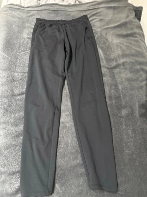 Svarta mjukisbyxor med resårmidja (SOC) - Svarta mjukisbyxor med enkel design och resår i midjan. Perfekta för chill dagar eller när du vill ha något bekvämt på dig. Materialet känns mjukt och stretchigt, och byxorna har en rak passform som ger en avslappnad vibe. Storleken är 158