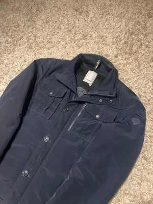 J. Lindeberg fieldjacket jacka marinblå svart herr  - J.Lindeberg fieldjacket i svart/marinblå färg. Storlek M med justerbar rygg för passform. Funkar bra till både höst och vinter. Nytt skick,inga defekter. Postas antigen samma dag som köp eller dagen därpå🙌💯