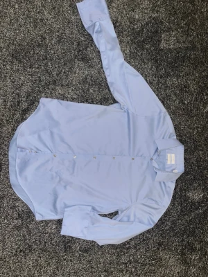 Ljusblå skjorta från Calvin Klein - Snygg ljusblå skjorta från Calvin Klein i slim fit-modell. Skjortan har klassisk krage, långa ärmar och knappar framtill. Tillverkad i bomull och polyester för en mjuk och lättskött känsla. Perfekt för dig som gillar stilrena och enkla plagg. Skjortan är storlek L. Retailpris på denna ligger på ungefär 800-1100 kronor. Endast använd vid ett tillfälle så skicket är 10/10. Tveka inte en sekund på att höra av dig vid funderingar😄. / Isak 
