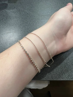 Silver/guld färgad armlänk från Claire’s - Säljer ett snyggt armband från Claire’s i Silver/guld färg med flera tunna kedjor och en rad med små glittrande stenar. Länken har en justerbar kedja och en liten bricka med logga. Perfekt för dig som gillar detaljer och vill ha något som sticker ut.
