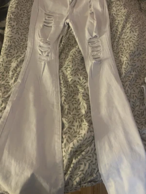 Vita bootcut jeans från SHEIN - Säljer ett par vita jeans från SHEIN i storlek S. Modellen är bootcut med breda ben och har snygga slitningar på framsidan. Jeansen har klassisk femficksdesign och är gjorda i ett jeansmaterial med lite stretch. Perfekt för dig som gillar trendiga och bekväma byxor.