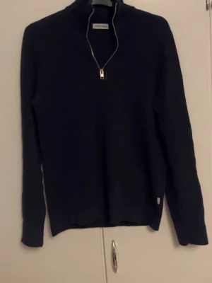 Mörkblå stickad tröja Jack & Jones - Snygg mörkblå stickad tröja från Jack & Jones med half zip och hög krage. Perfekt för dig som gillar enkel och stilren design. Långärmad modell som passar till jeans eller chinos. Tröjan har en normal passform och är gjord i mjukt material.
