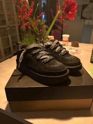 Uggs lowmel  - Säljer ett par svarta UGG sneakers med plattformssula och rund tå. Skorna har snörning med breda, mönstrade skosnören och en mix av mocka och mesh-material. Perfekta för dig som gillar chunky stil och vill ha något som sticker ut. De är i storlek 41 men passar 42, säljer för de inte används.