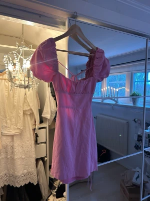 Rosa kortklänning med puffärmar - Säljer en söt rosa kortklänning med puffiga kortärmar och snörning i ryggen.