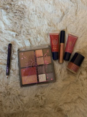 Q-KI sminkset med palett och gloss - Säljer ett sminkset från Q-KI med en multifunktionell palett i sopiga nude- och bruna toner, två läppglans i rosa och röd sopig färg, ett guldigt läppglans, en ögonpenna och ett nagellack i nude. Perfekt för dig som gillar att experimentera med olika looks.