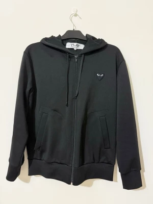 CDG Hoodie ( comme des garcons ) - Riktigt snygg CDG hoodie med dragkedja. Den är som ny i skick, förutom att ena fickan gått lite sönder men inget man märker. Kostar 50 spänn att sy ihop den om man vill göra de. Storleken är M men passar även S. Hör av er vid frågor, mvh.