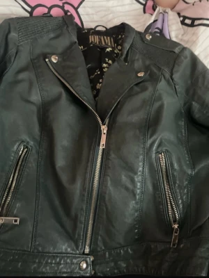 Svart skinnjacka från Jofama - Säljer en svart skinnjacka från Jofama by Marie Serneholt. Jackan har coola detaljer med dragkedjor framtill och på fickorna, samt snygga axelpartier. Äkta skinn 