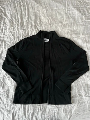 Svart merino full zip från these glory days - Säljer en svart merino full zip från these glory days. Den har ett litet märke på vänstra ärmen, som syns på andra bilden, men inget man tänker på. Annars har den inget annat anmärkningsvärt och är i bra skick övrigt. | Fråga på om det är något!