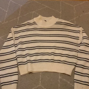 Vit och svart randig stickad tröja H&M - Säljer en vit stickad tröja från H&M i storlek XXS med svarta horisontella ränder. Tröjan har en croppad passform, ribbad hals och muddar samt långärmade ärmar. Perfekt för dig som gillar klassisk stil med en modern twist. 