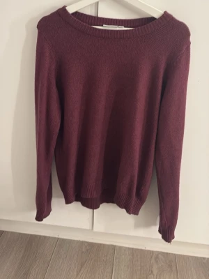 Vinröd stickad tröja från Vila - Mysig vinröd stickad tröja från Vila i storlek M. Tröjan har rund halsringning, ribbade muddar vid ärmslut och nederkant samt lång ärm. Perfekt för kyligare dagar och enkel att matcha med jeans eller kjol. Knappt använd.