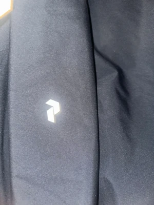 Svart vindjacka Peak Performance  - Svart vindjacka från Peak Performance i storlek S. Jackan har huva med snörning, hel dragkedja framtill och två sidofickor. Materialet är syntet och jackan har en stilren look med diskret logga på bröstet. Perfekt för blåsiga dagar och outdoor. Passar även M