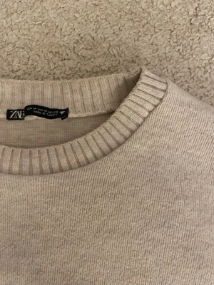 stickad tröja - Säljer en beige stickad tröja från Zara med rund hals och ribbade detaljer vid kragen. Jätte snygg och passar till alla byxor🤩