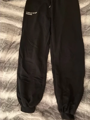 Svarta mjukisbyxor från Only Trend - Svarta mjukisbyxor från Only Trend med tryck på ena benet o storlek L. Byxorna har resår och snörning i midjan samt ribbade muddar vid bensluten. Perfekta för chill eller träning, tillverkade i mjukt bomullsmaterial för extra komfort. Säljer även en tillhörande tröja i en annan annons. 😁