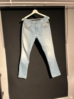 Replay ljusblå jeans, modell Anbass - Säljer ett par ljusblå Replay Anbass jeans med klassisk femficksdesign och snyggt tapered snitt. Jeansen har normal passform. Perfekt för dig som gillar stilrena och bekväma jeans med modern look.