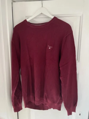 Vinröd stickad tröja från GANT 3XL - Säljer en vinröd stickad tröja från GANT i storlek 3XL. Tröjan har rund hals, lång ärm och diskret logga på bröstet. Materialet är mjukt och stickat, perfekt för kyliga dagar. Passformen är loose och färgen är mörkt vinröd.