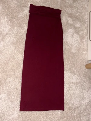 Vinröd långkjol från Gina Tricot - Säljer en vinröd långkjol från Gina Tricot i storlek S. Kjolen har en tight passform och är gjord i mjukt stretchigt material som sitter snyggt mot kroppen. Perfekt att matcha med en croppad topp eller stickad tröja för en cool look.