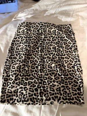 Leopardmönstrad kortkjol🐆💫✨ - Säljer en snygg kortkjol från MISU ( Ett märke från New Yorker.) med leopardmönster i svart, beige och bruna toner. Kjolen har en rak och tight passform som ger en cool vibe. Materialet är mjukt och stretchigt polyester, perfekt för att skapa en trendig look.🐆✨