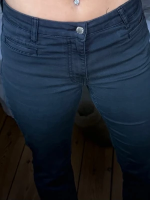 Mörkblå midwaist jeansbyxor - Snygga mörkblå jeansbyxor med midwaist passform och raka ben. Klassisk femficksdesign med silverfärgad knapp och bälteshällor. Materialet är mjukt och stretchigt jeans, vilket gör dem bekväma att bära hela dagen. Perfekt för dig som gillar en enkel och stilren look.Dem är lite korta för mig som är 163 om man vill att dem ska gå ner till marken, dem går ungefär till mina anklar. 