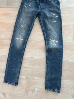 Replay Mickym blå jeans, slim tapered - Säljer ett par blå Replay Mickym jeans med slim tapered fit. Jeansen har slitna detaljer och snygg tvätt, klassisk femficksmodell och brunt Replay-läderpatch bak. Passar dig som gillar smalare ben och modern look.