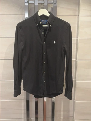 Svart skjorta från Polo Ralph Lauren XS - Säljer nu denna sjukt snygga skjortan från Ralph Lauren då den inte används, den är i storlek XS men sitter som en S. 