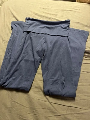 Blå bootcut leggings från H&M - Säljer ett par blå leggings från H&M med bootcut-snitt och hög midja. De är gjorda i mjukt och stretchigt bomullsmaterial som sitter skönt mot kroppen. Perfekta för dig som gillar en avslappnad och trendig look. Passar dig som vill ha bekväma byxor med lite utsvängda ben.