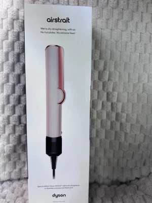 Dyson Airstrait plattång rosa/bronze - Special edition Dyson Airstrait plattång i färgerna strawberry bronze och blush pink. Plattången använder luft för att räta ut håret från vått till torrt utan extrema värmenivåer. Modern design med slät, avlång form och medföljande förvaringsväska i svart och rosa.