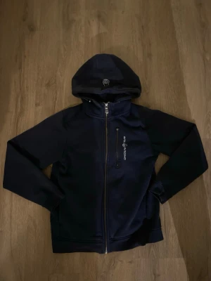 Mörkblå Sail Racing zip hoodie/160 - Blå svart snygg hoodie som håller värmen väldigt bra. Säljer för den är för liten nu.