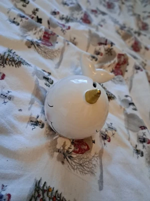 Spargris – Vit keramik – Söt valdesign - Säljes: Fin spargris i form av en vit val. Gjord i keramik med glansig yta. En charmig spargris formad som en narval med en gyllene horn. Perfekt för att spara pengar på ett roligt sätt.  * Helt ny skick (se bilder för detaljer). * Material Keramik *Färg Vit * Uttag på undersidan för enkel åtkomst till mynten.  Skickas väl emballerad via posten och köparen står för frakten.   Vid övriga frågor skicka gärna meddelande. Lämnar självklart god omdömen om köparen gör det.