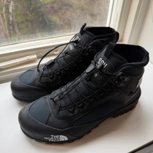 The North Face x Undercover - Säljer ett par svarta kängor från The North Face i samarbete med Undercover. Modellen har robust Vibram-sula, snörning och detaljer med texten SOUKUU. Materialet är en mix av syntet och skinn, perfekt för dig som gillar street och outdoor. Storlek EU 43, US 10.