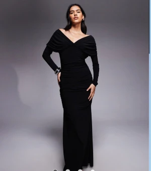 Svart långklänning med offshoulder - Elegant svart långklänning med offshoulder och v-ringad omlott upptill. Lång på mig som är 165 cm. Endast använd en gång så i toppskick!!