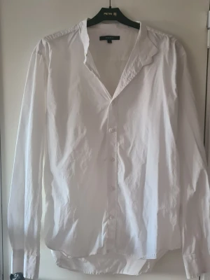 Vit skjorta från GANT i bomull - Vit skjorta från GANT i storlek L, tillverkad i 100% bomull. Klassisk design med knappar framtill och lång ärm. Skjortan har en enkel krage och en clean look som funkar till många olika stilar.