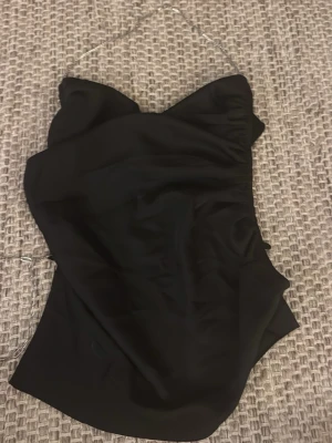 Svart tubtopp från Fashion Nova - Säljer en svart tubtopp från Fashion Nova med silvrig kedja. Öppen rygg som hålls utav silver kedjan. 