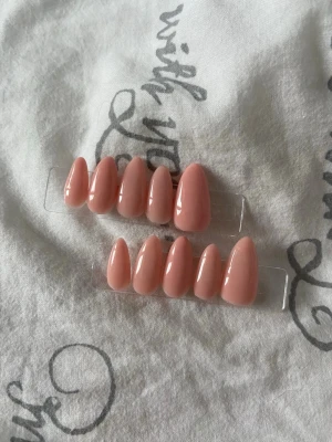 Rosa lösnaglar i mandelform - Säljer ett set med glansiga lösnaglar i en mjuk rosa nyans. Naglarna har en snygg mandelform och kommer på plastställ för enkel applicering. Perfekt för dig som vill ha en fräsch och trendig look utan att gå till salong.