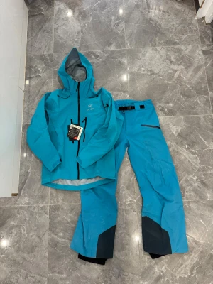 Blå täckbyxor från Arc'teryx Gore-Tex - Jackan är helt ny och oanvänt. Storlek S men är större passar som M. Byxorna är storlek M och använda några gånger. Hela settet passar Storlek M 