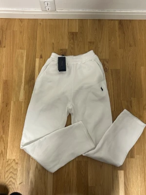 Vita mjukisbyxor från Polo Ralph Lauren - Säljer ett par fräscha vita mjukisbyxor från Polo Ralph Lauren med klassisk broderad logga på benet. Byxorna har elastisk midja och är gjorda i mjukt bomullsmaterial. Perfekt för chill dagar och har en clean look.