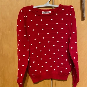 Barnkläder, barntröja, Röd prickig stickad tröja H&M - Röd stickad tröja från H&M med vita prickar över hela tröjan. Rund halsringning och långa ärmar. Perfekt för dig som gillar färg och mönster. Snygg till jeans eller kjol!