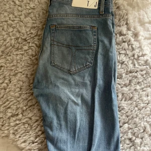 Ljusblå jeans med klassisk passform - Säljer ett par ljusblå jeans med klassisk femficksdesign och snygga kontrastsömmar. Jeansen har en enkel bakficka och är perfekta för en avslappnad stil. Passar dig som gillar tidlösa och bekväma jeans.