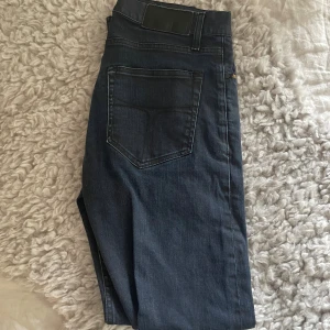 Mörkblå jeansbyxor med rak passform - Snygga mörkblå jeansbyxor med klassisk femficksdesign och rak passform. Jeansen har en enkel bakficka och subtila sömmar, perfekta för en stilren look. Tillverkade i mjukt jeansmaterial som sitter skönt hela dagen.