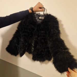 Pälsjacka  - Fluffig svart pälsjacka från DM Retro. Jackan har ett coolt, lyxigt uttryck och är lite fodrad på insidan för extra komfort. Perfekt för dig som vill sticka ut med en statementjacka i garderoben.