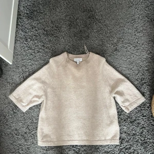 Beige stickad tröja & Other Stories - Supermysig beige stickad tröja från & Other Stories med rund halsringning och halvlånga ärmar. Perfekt för lager-på-lager och chill dagar. Enkel och stilren design som funkar till det mesta.