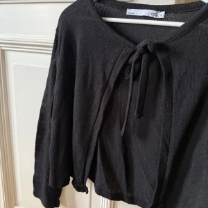 Svart kofta med knyt framtill - Svart kofta från 157 i stickat material. Koftan har långa ärmar och en snygg knytning framtill vid halsen. Perfekt att slänga över en linne eller tröja! 💖💖