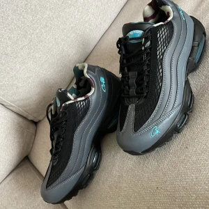 Nike sneakers svart/grå camo - Nike sneakers i svart och grått med coola blå detaljer och camouflagemönstrat foder. Ovandelen har mesh och skinnpaneler, snörning framtill och en chunky sula. Perfekt för dig som vill sticka ut med en unik och sportig look.